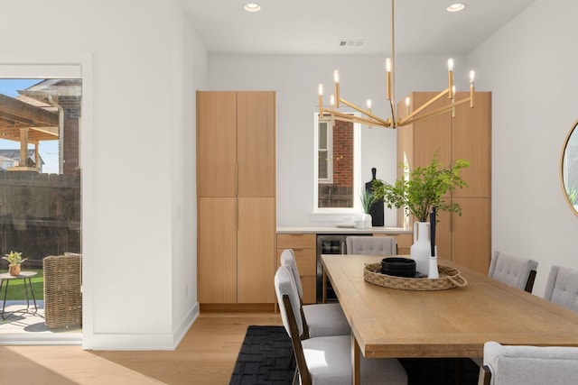 dining space featuring a chandelier, wine cooler, and light hardwood / wood-style floors