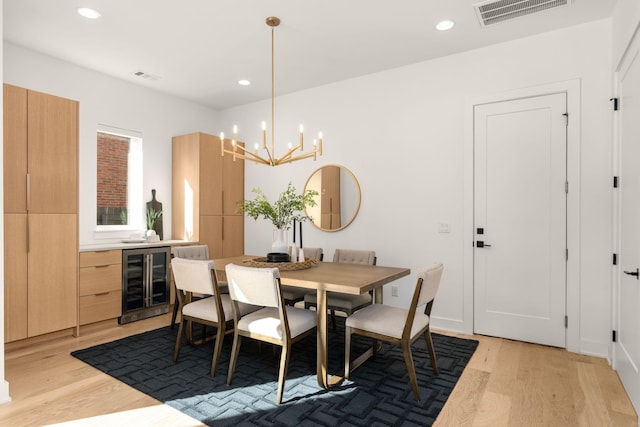 dining room featuring wine cooler, light hardwood / wood-style flooring, and an inviting chandelier