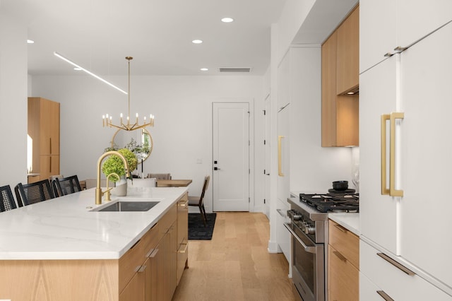 kitchen featuring decorative light fixtures, sink, a kitchen bar, premium appliances, and a center island with sink