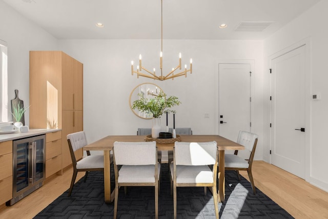 dining room featuring beverage cooler, a chandelier, and light hardwood / wood-style floors