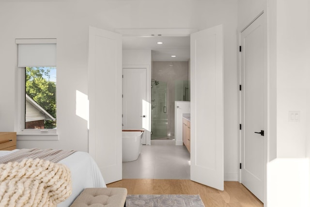 bedroom with ensuite bath and light hardwood / wood-style flooring