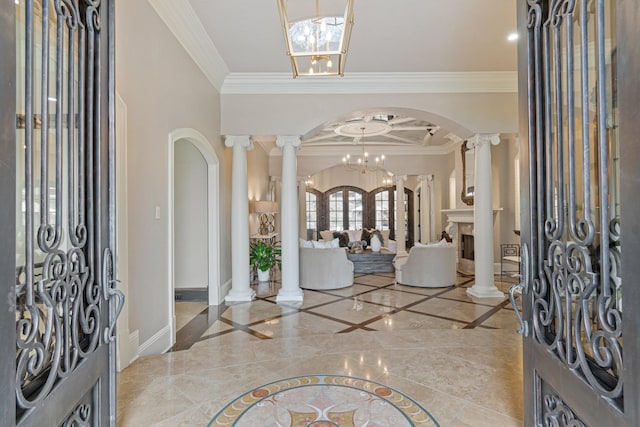 entryway with an inviting chandelier, crown molding, french doors, and ornate columns