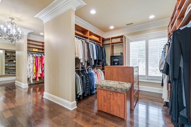 spacious closet featuring an inviting chandelier, decorative columns, and dark hardwood / wood-style floors