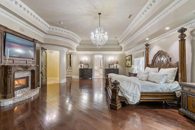 bedroom featuring a notable chandelier, wood-type flooring, ornamental molding, and a premium fireplace