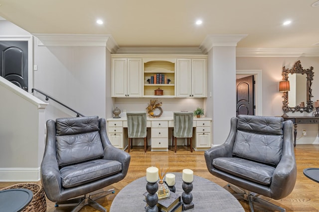 sitting room with crown molding, built in desk, and light hardwood / wood-style flooring