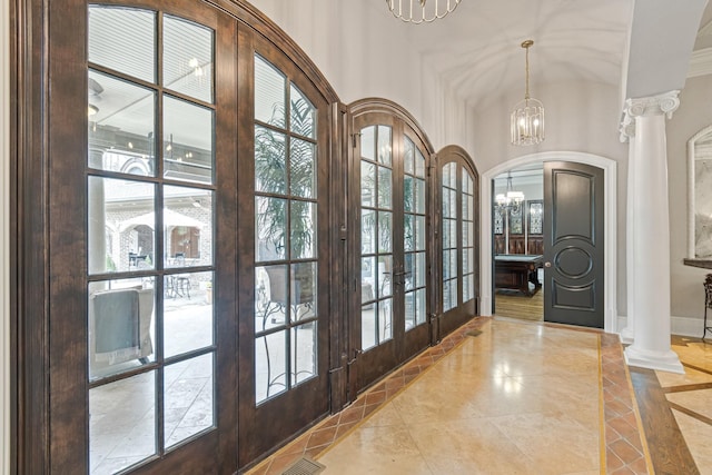 interior space with ornate columns, plenty of natural light, an inviting chandelier, and french doors