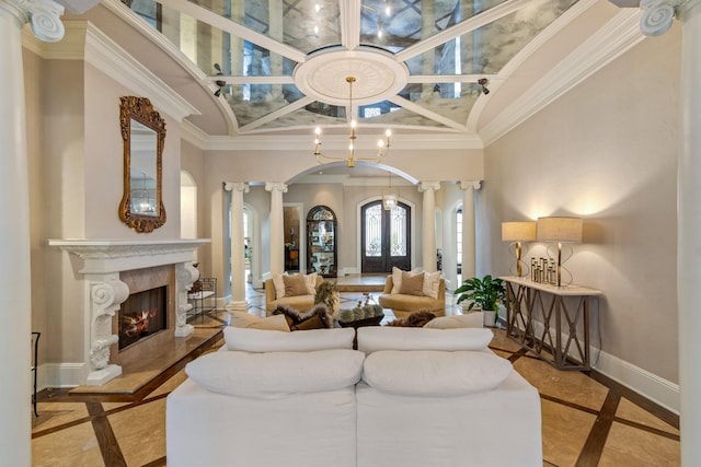 living room featuring a towering ceiling, ornamental molding, a fireplace, and decorative columns