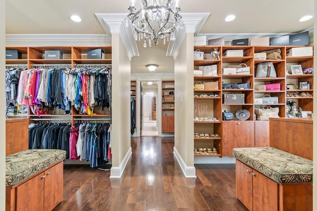 walk in closet with dark wood-type flooring and an inviting chandelier