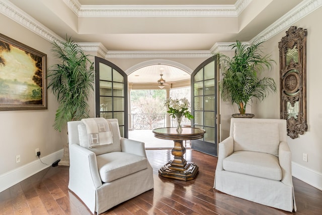 living area with dark hardwood / wood-style flooring, a tray ceiling, and crown molding