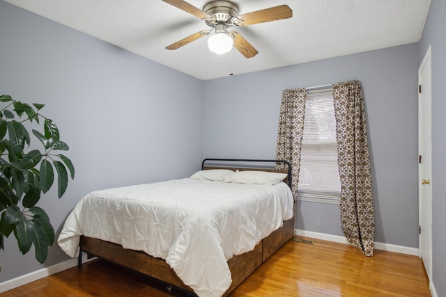 bedroom with ceiling fan, light hardwood / wood-style flooring, and a textured ceiling