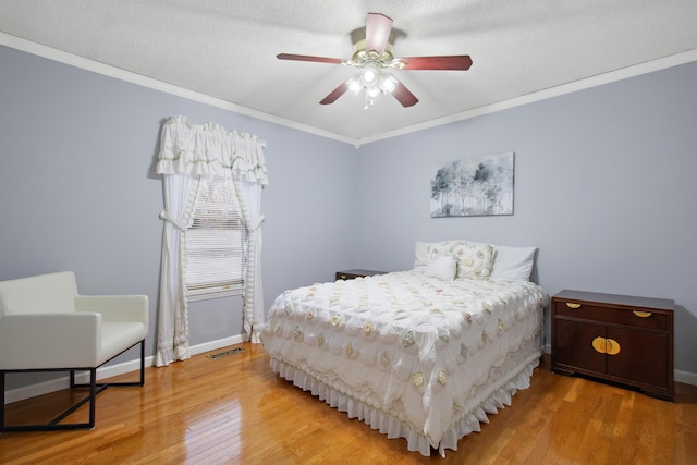 bedroom featuring hardwood / wood-style floors, crown molding, a textured ceiling, and ceiling fan