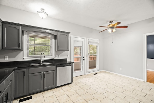 kitchen with gray cabinets, dishwasher, sink, ceiling fan, and a textured ceiling