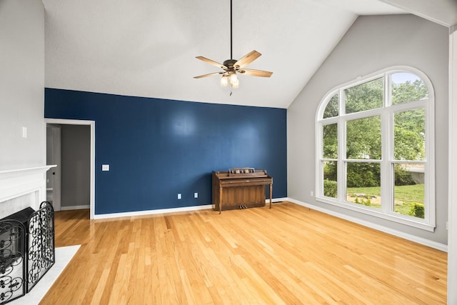 unfurnished living room with ceiling fan, wood-type flooring, a premium fireplace, and high vaulted ceiling