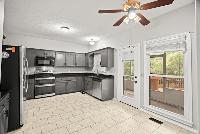 kitchen with gray cabinets, sink, light tile patterned floors, stainless steel appliances, and a textured ceiling