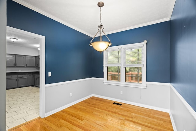 unfurnished dining area featuring ornamental molding and light hardwood / wood-style flooring