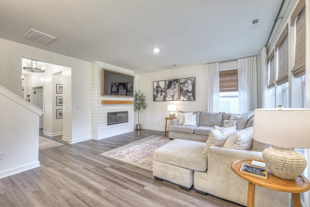 living room with a large fireplace, a chandelier, and hardwood / wood-style floors