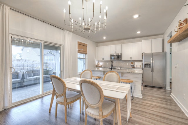 dining space featuring a notable chandelier and light wood-type flooring