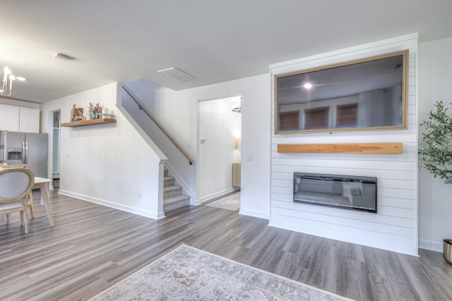 kitchen featuring white cabinetry, a fireplace, stainless steel fridge, and hardwood / wood-style floors