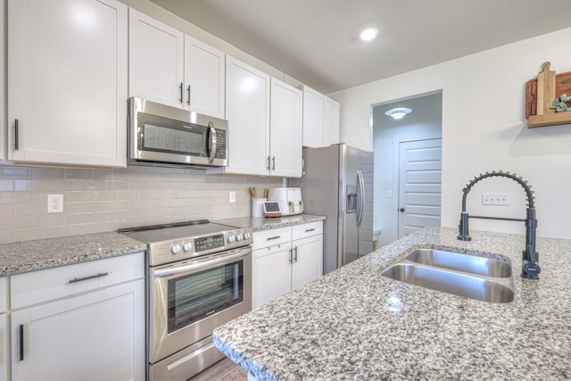 kitchen featuring white cabinetry, stainless steel appliances, sink, and light stone counters