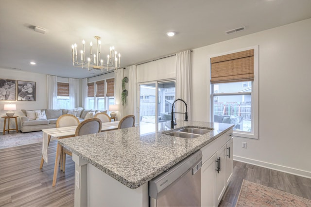 kitchen featuring pendant lighting, sink, dishwasher, a kitchen island with sink, and white cabinets