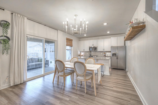 dining room featuring sink, a notable chandelier, and light hardwood / wood-style flooring