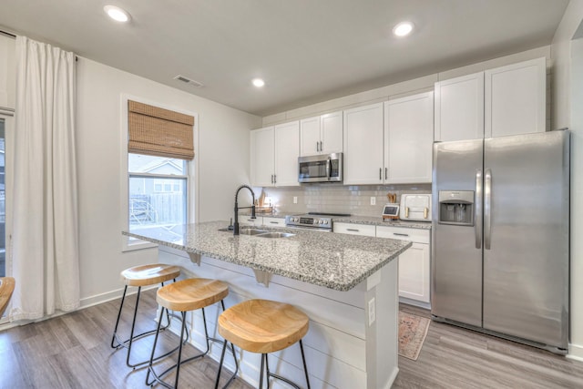 kitchen featuring stainless steel appliances, white cabinetry, sink, and a kitchen island with sink