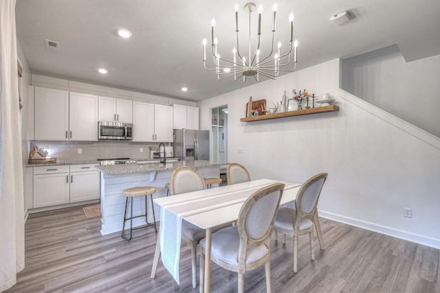 dining room with a chandelier, sink, and light hardwood / wood-style flooring