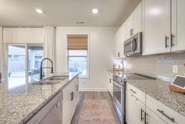 kitchen featuring stainless steel appliances, white cabinetry, sink, and tasteful backsplash