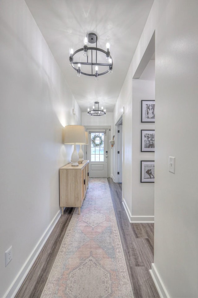 hallway featuring wood-type flooring and a chandelier