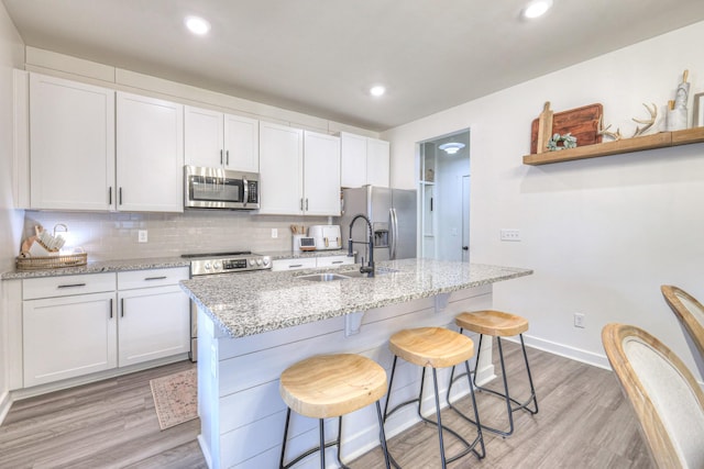 kitchen featuring sink, light stone countertops, white cabinets, and appliances with stainless steel finishes