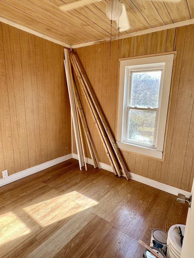 unfurnished room with wooden ceiling, wood finished floors, baseboards, and wood walls