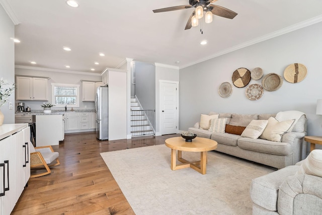 living room with light hardwood / wood-style flooring, ornamental molding, and ceiling fan