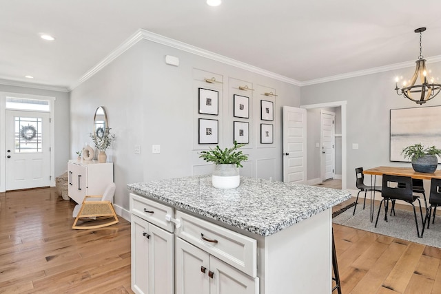 kitchen with white cabinetry, a center island, light stone countertops, and light wood-type flooring