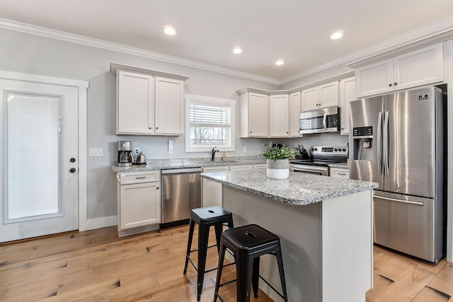 kitchen featuring sink, crown molding, appliances with stainless steel finishes, a center island, and white cabinets