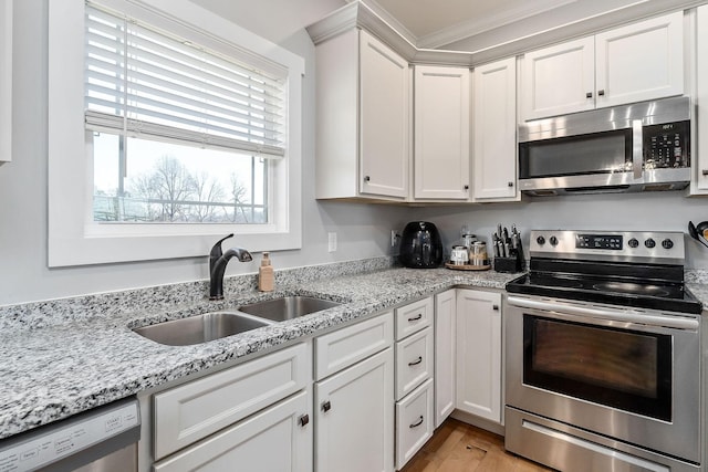 kitchen with sink, white cabinetry, light stone counters, light hardwood / wood-style flooring, and appliances with stainless steel finishes