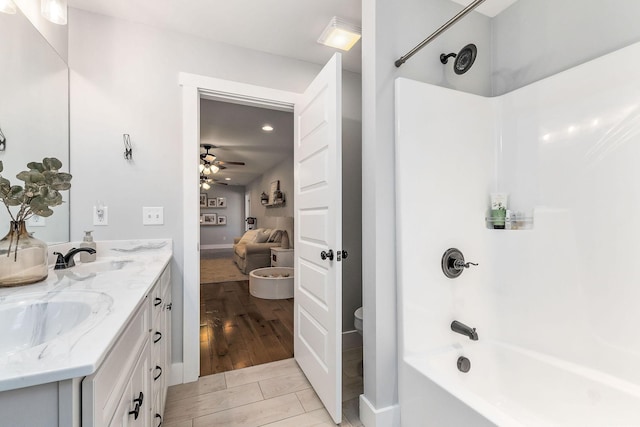 full bathroom featuring wood-type flooring, vanity, ceiling fan, toilet, and bathing tub / shower combination