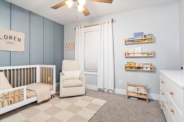 bedroom with a nursery area, light colored carpet, and ceiling fan