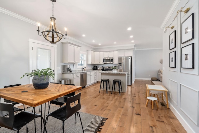 dining room featuring crown molding, sink, a notable chandelier, and light hardwood / wood-style floors