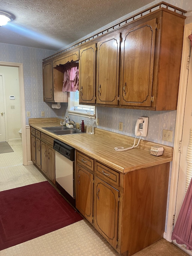 kitchen with sink, a textured ceiling, and white dishwasher