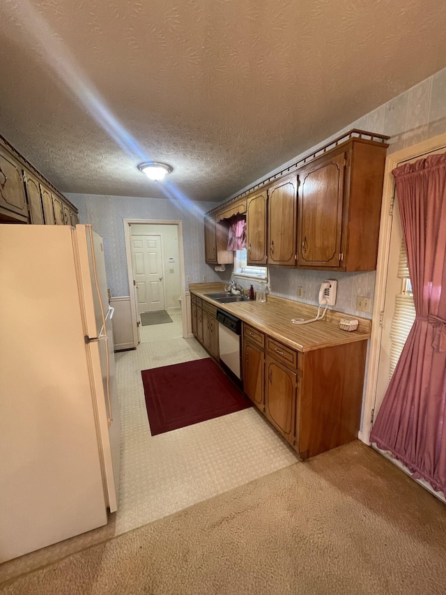 kitchen with sink, white appliances, light colored carpet, and a textured ceiling