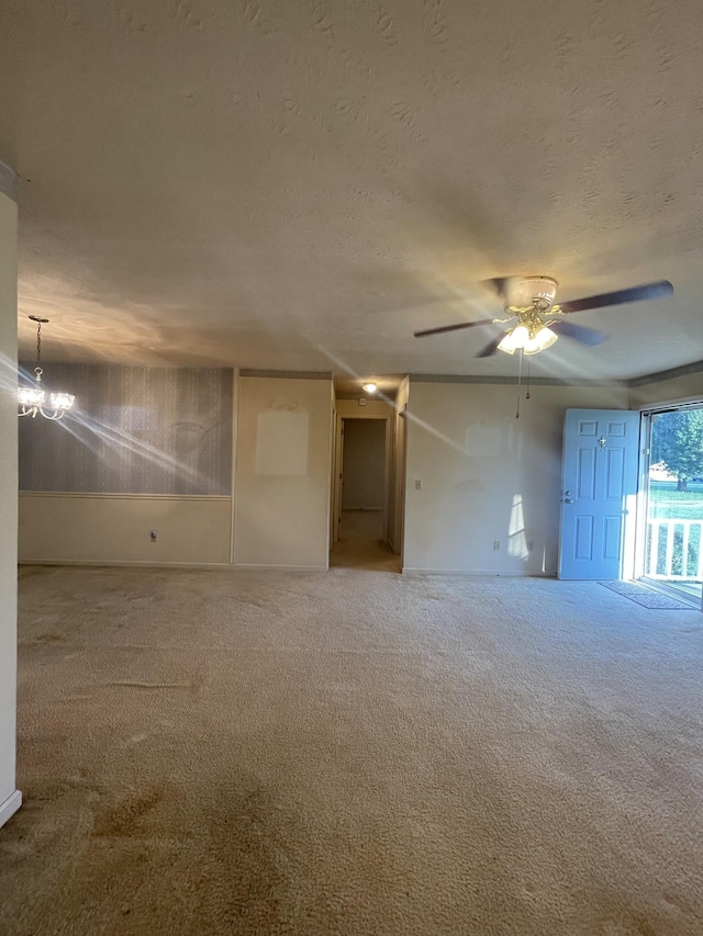 carpeted empty room featuring ceiling fan with notable chandelier and a textured ceiling