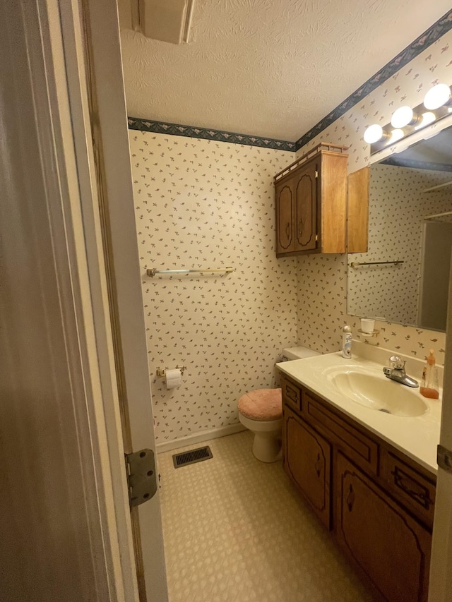 bathroom featuring vanity, toilet, and a textured ceiling