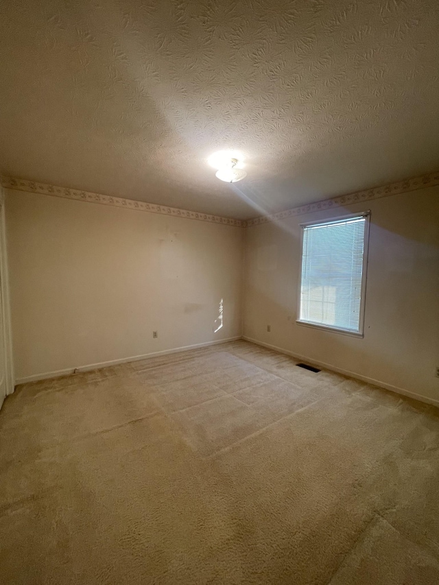 carpeted empty room with a textured ceiling