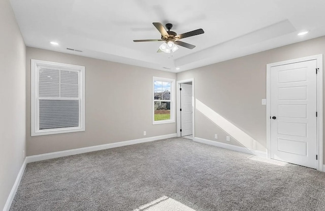 unfurnished room with ceiling fan, carpet flooring, and a raised ceiling