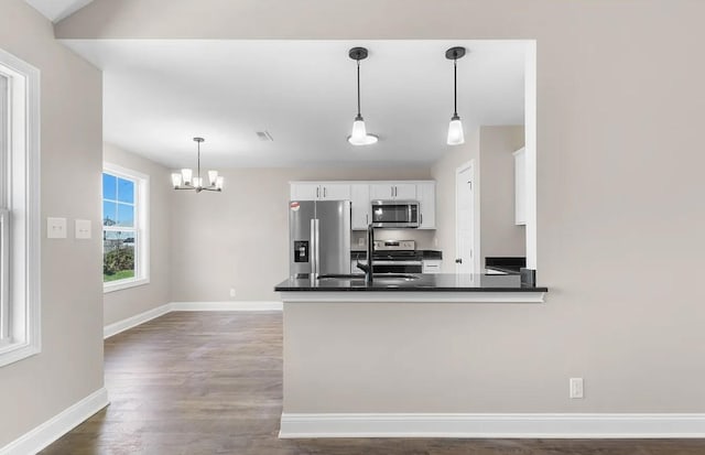 kitchen featuring white cabinets, dark hardwood / wood-style flooring, hanging light fixtures, kitchen peninsula, and stainless steel appliances