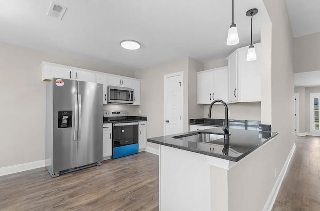 kitchen with appliances with stainless steel finishes, pendant lighting, sink, white cabinets, and kitchen peninsula