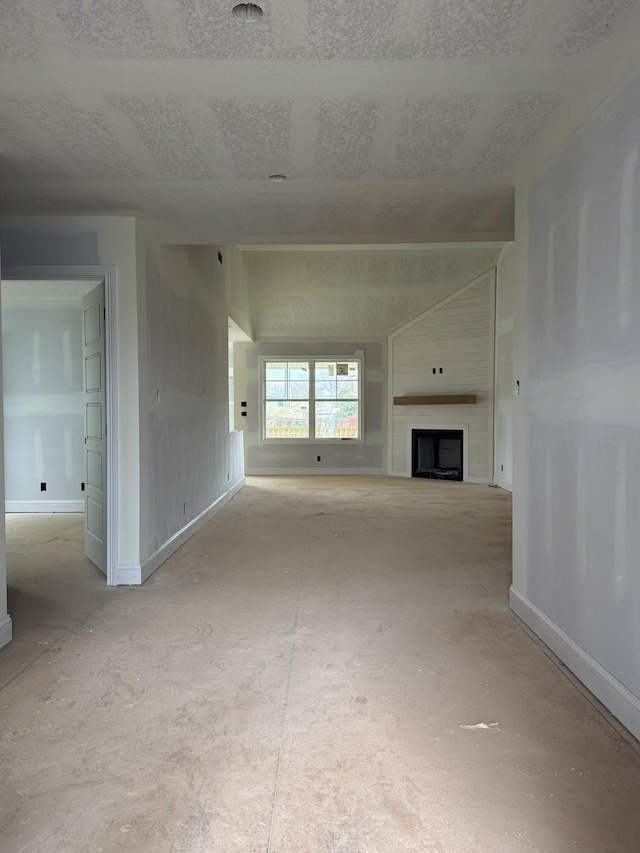 unfurnished living room with baseboards, a textured ceiling, and a fireplace