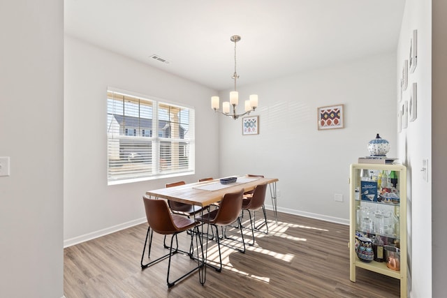 dining area featuring hardwood / wood-style flooring and an inviting chandelier