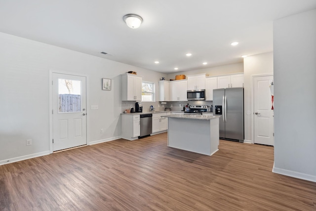 kitchen featuring stainless steel appliances, white cabinetry, a kitchen island, and light hardwood / wood-style floors