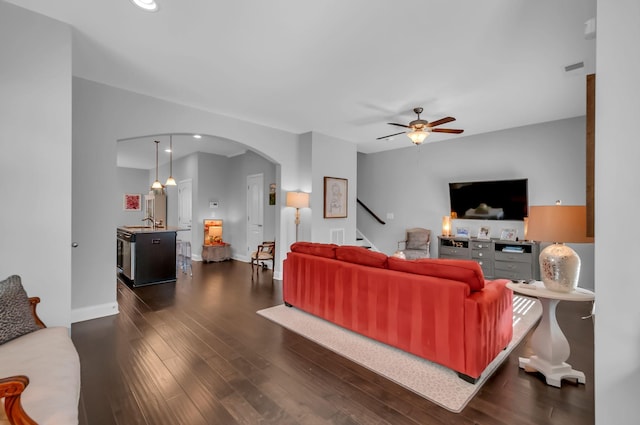 living room featuring sink, dark wood-type flooring, and ceiling fan